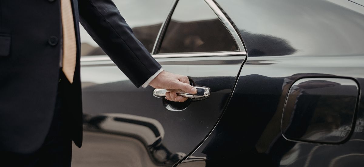 qrun-client-car-door-professional Professional QRun driver opening car door for a suited client outside a Bristol office